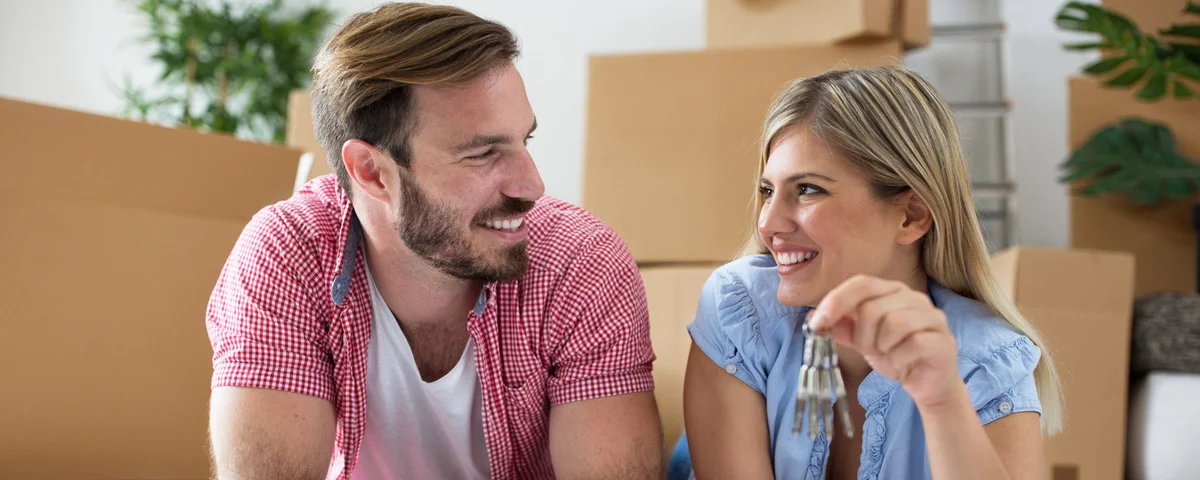 Un jeune couple heureux économise de l'argent pour son prochain investissement, assis au milieu de cartons.