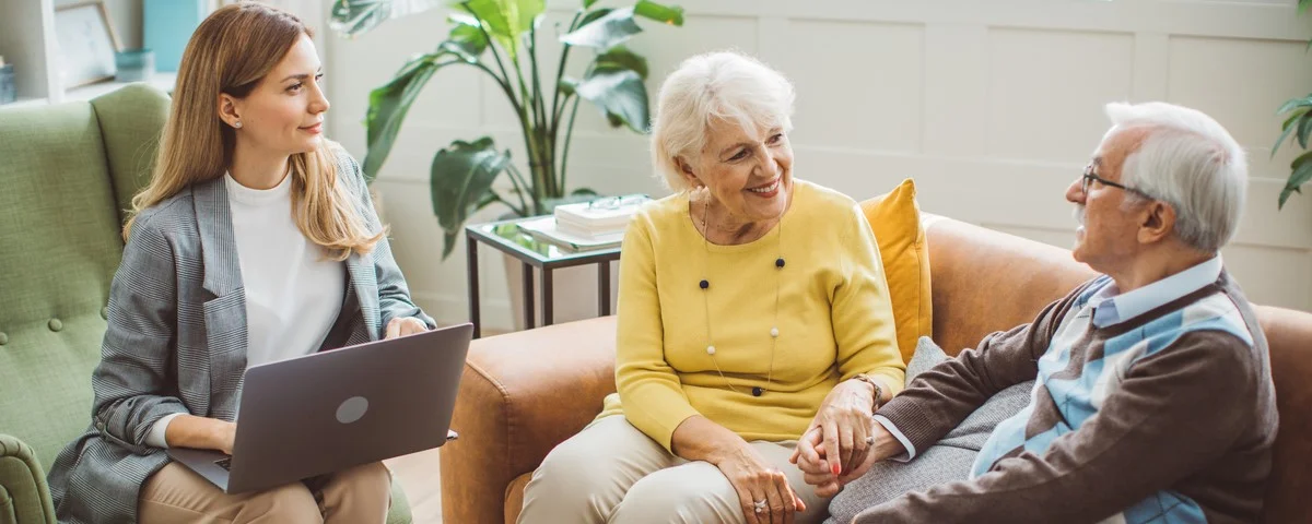 Couple de seniors s'entretenant avec une conseillère financière ou immobilière à domicile.