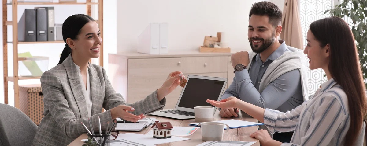 Agent immobilier concluant un contrat avec un jeune couple dans un bureau. 