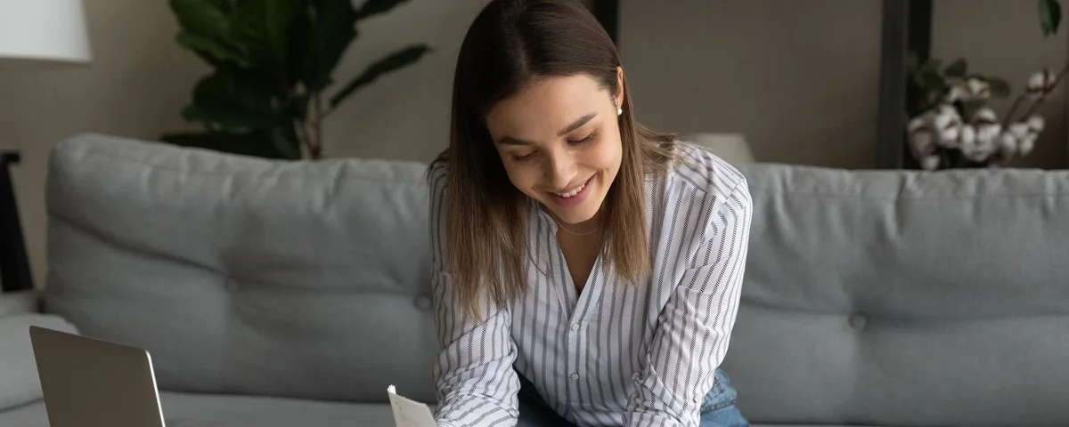 Jeune femme heureuse tenant des billets de banque dans ses mains, calculant ses dépenses, payant des factures ou des services en ligne dans une application informatique, se sentant satisfaite d'avoir assez d'argent, concept de paiement d'investissement.