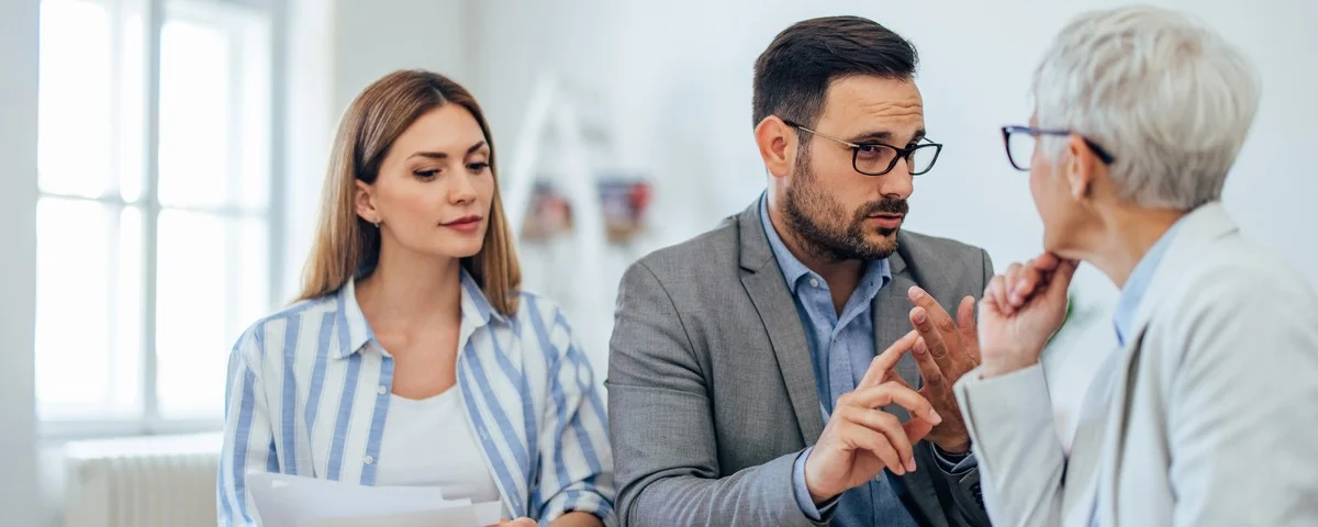 Agent d’assurance avec des clients en train de discuter au bureau.