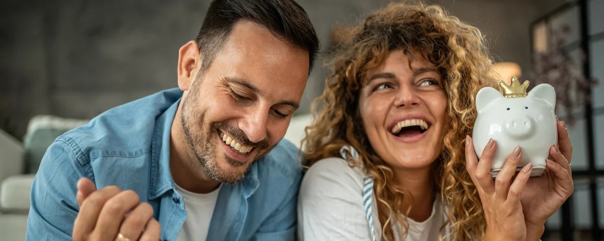 Un jeune couple heureux économise de l'argent pour son prochain investissement, son prochain achat ou ses prochaines vacances.