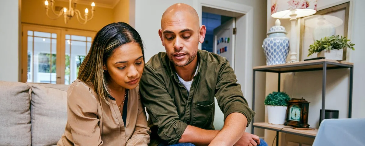 Photo d’un jeune couple en train de revoir ses finances tout en utilisant son ordinateur portable