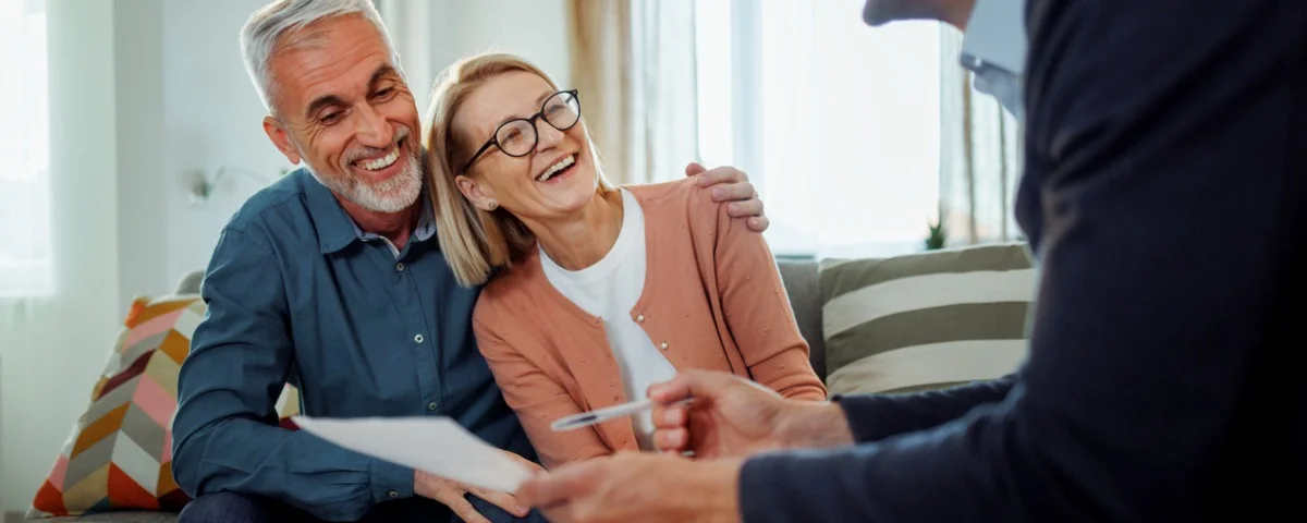 Agent d'assurance masculin présentant des documents à un couple d'âge mûr chez eux.