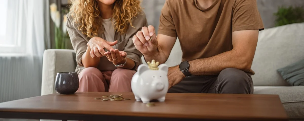 Un couple d'adultes, la femme et le mari, économisent ensemble de l'argent dans la tirelire.