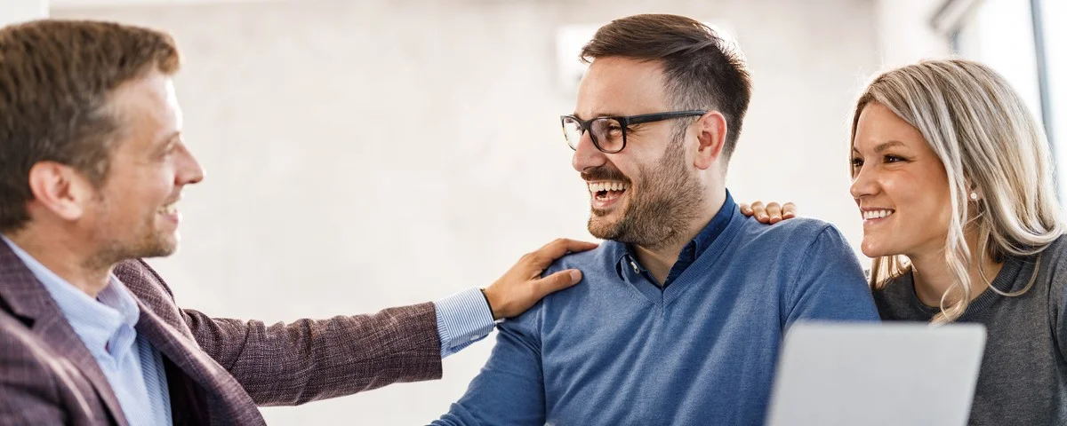 Un jeune couple heureux a conclu un accord avec son agent d'assurance lors d'une réunion au bureau.