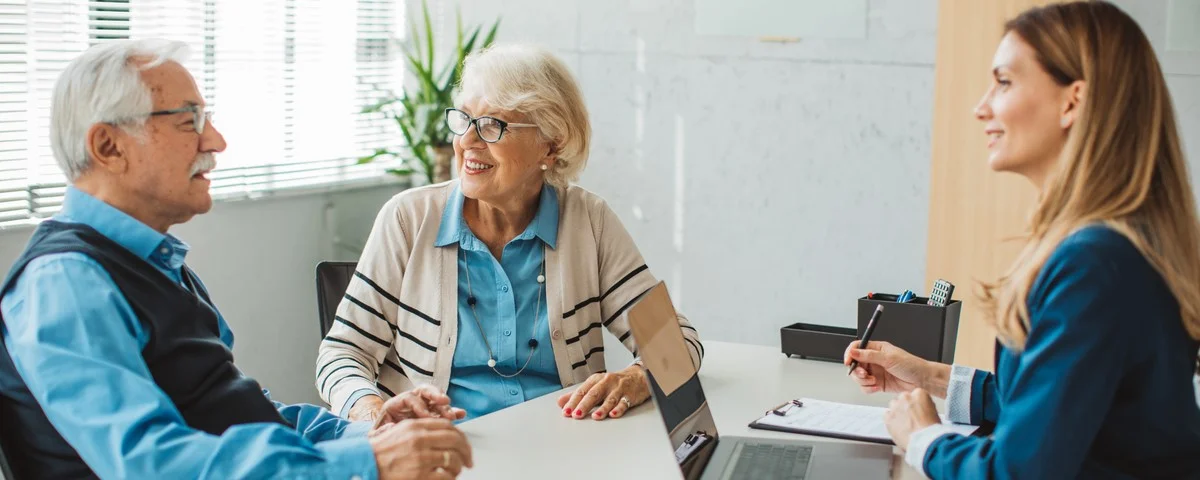 Couple de seniors s'entretenant avec une conseillère financière ou immobilière à son bureau.