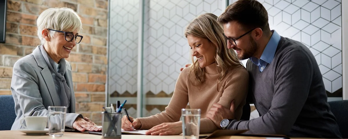 Couple heureux signant un contrat lors d'un entretien avec leur agent d'assurance au bureau.