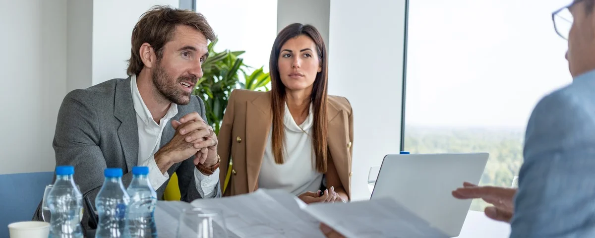 Hommes d'affaires assis à la table de conférence et discutant de plans de projets sur des feuilles.