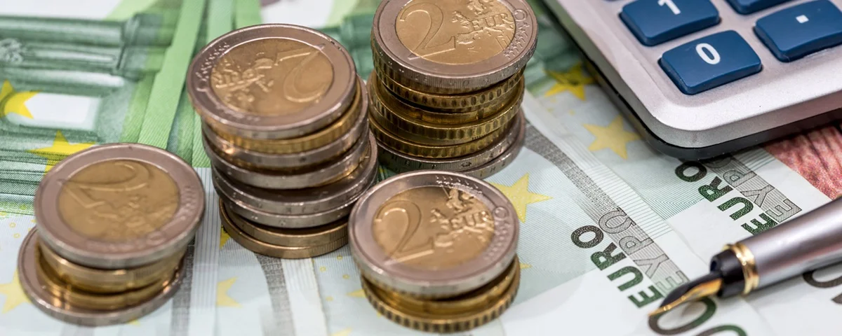 Billets de 100 euros avec stylo à encre, pièce de monnaie et calculatrice.