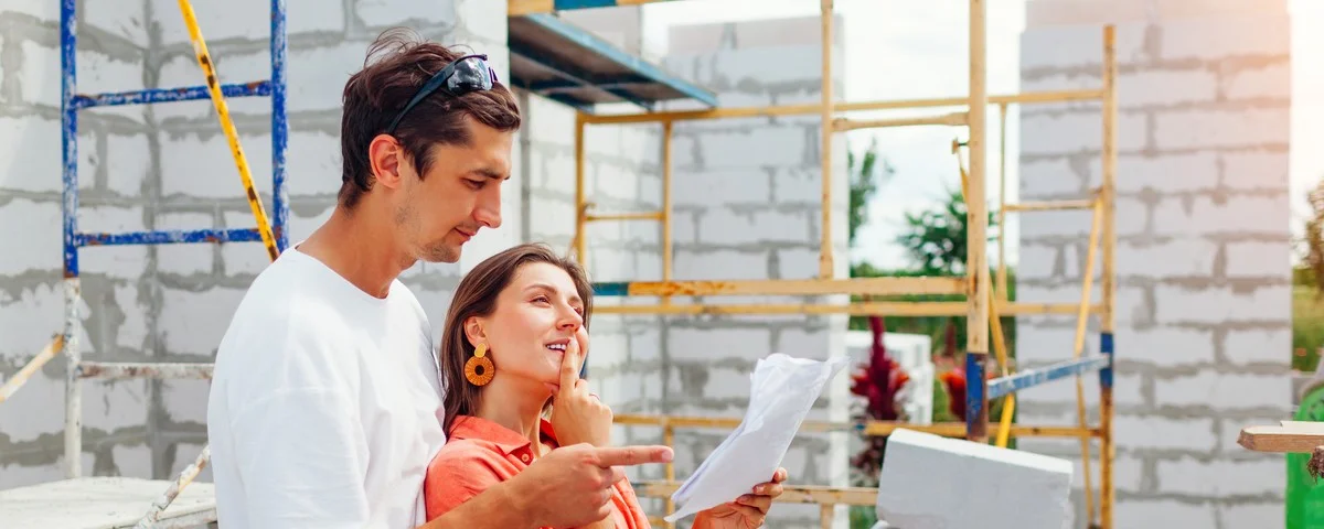 Jeune couple heureux vérifiant leur future maison en construction. 