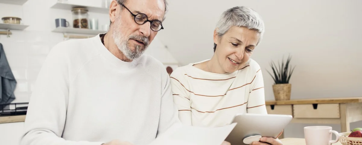 Jeune couple observant attentivement ses économies et ses investissements, représentés par des piles de pièces de monnaie et une tirelire, symbolisant la planification financière et la réalisation d'objectifs.