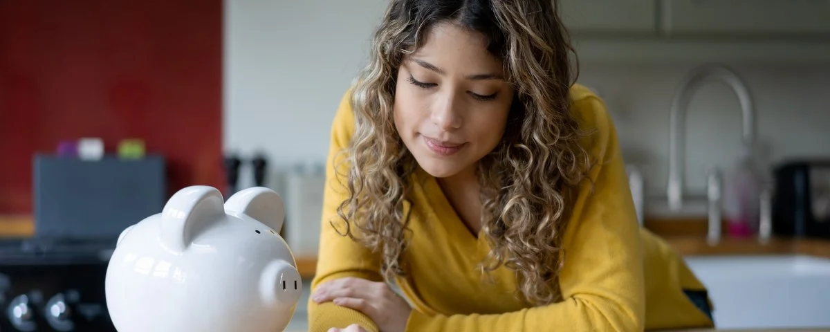 Jeune femme réfléchie comptant ses pièces de monnaie sur le comptoir de la cuisine à la maison.