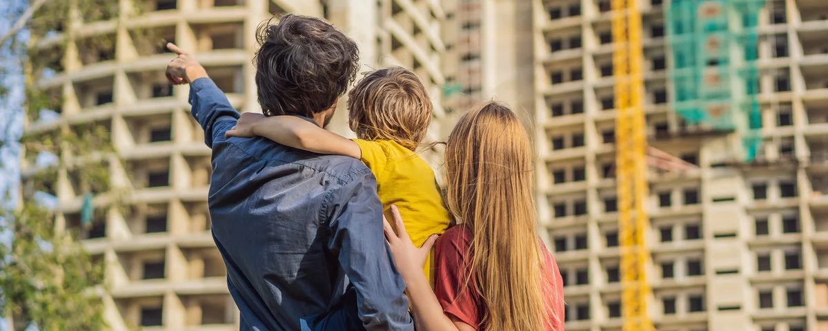 Une famille composée d'une mère, d'un père et d'un fils regardant leur nouvelle maison en construction, planifiant l'avenir et rêvant. 