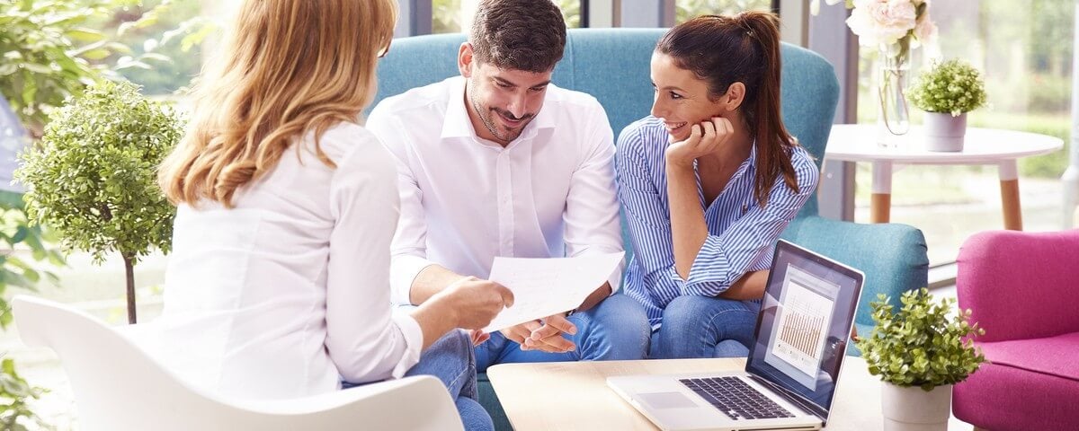 Plan d'un jeune couple discutant de leurs projets d'épargne avec une femme d'affaires. Une belle femme et un bel homme sont assis sur un canapé tandis que la conseillère leur donne des conseils.