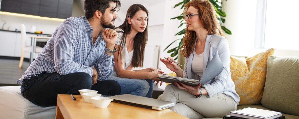 Une agente immobilière propose une assurance habitation et une assurance vie à un jeune couple.