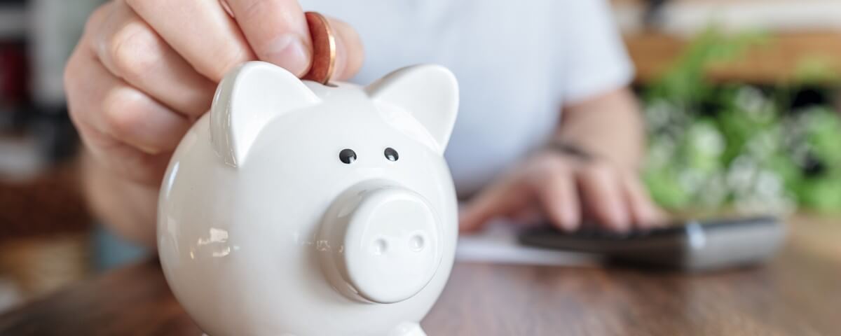 Concept représentant un homme déposant une pièce dans une tirelire rose, sur le thème de l'épargne et des finances