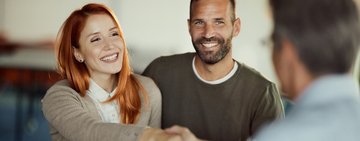 Un jeune couple heureux est parvenu à un accord satisfaisant avec son agent lors d'un rendez-vous au bureau.